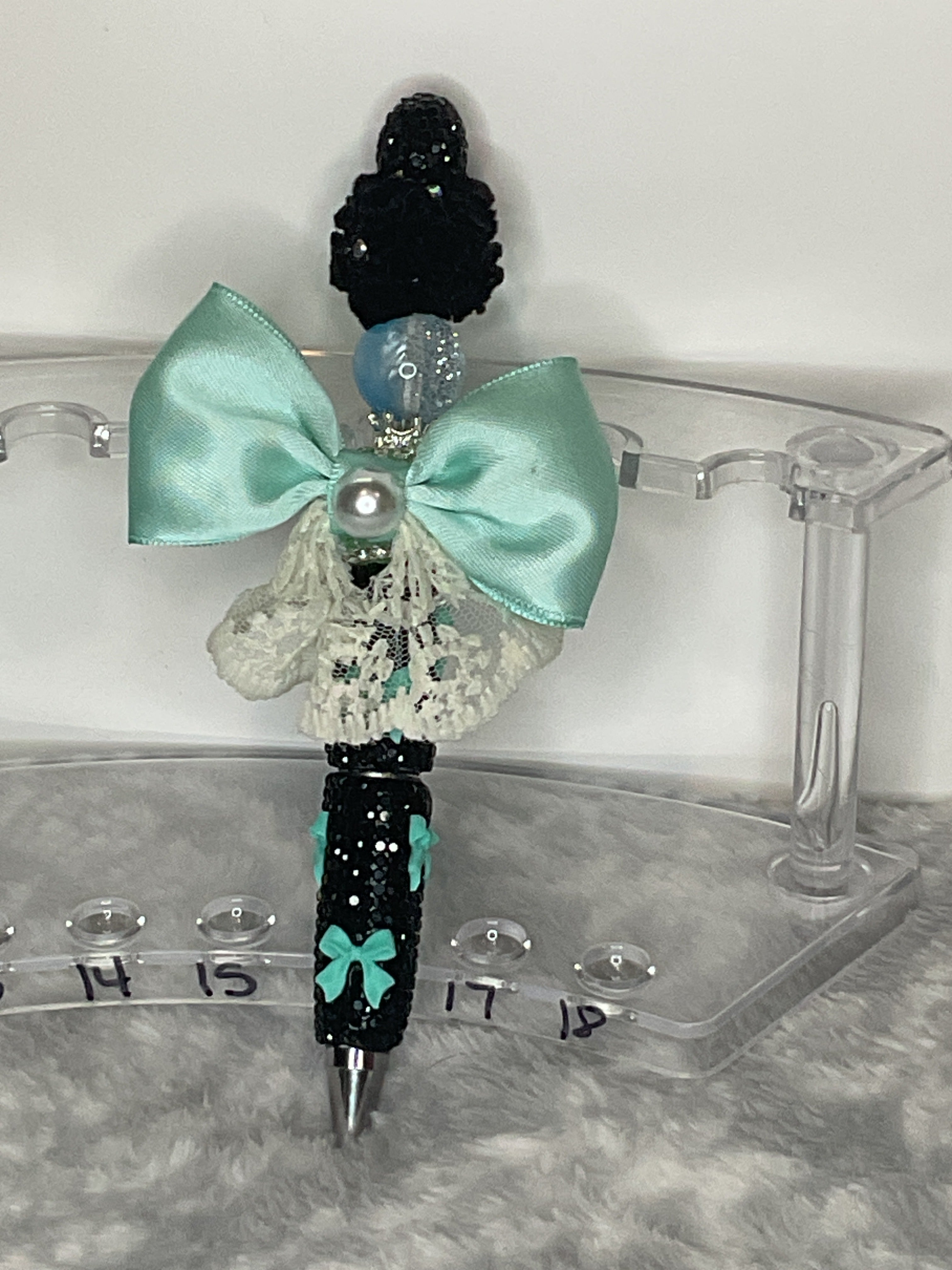 Teal bow on a black pen with teal bows
